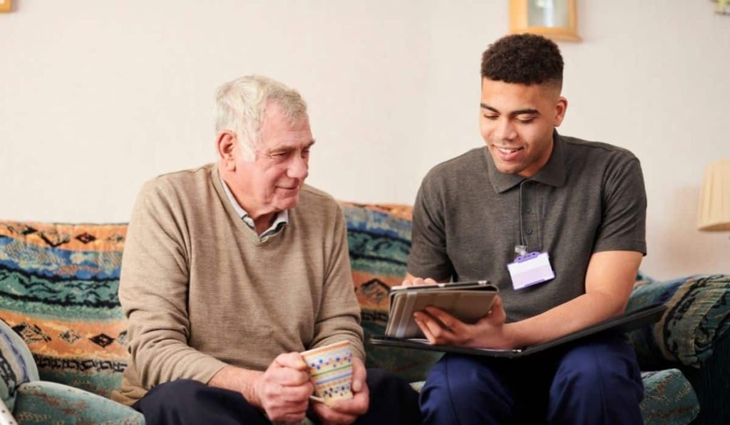 ndis support worker helping elderly disabled man